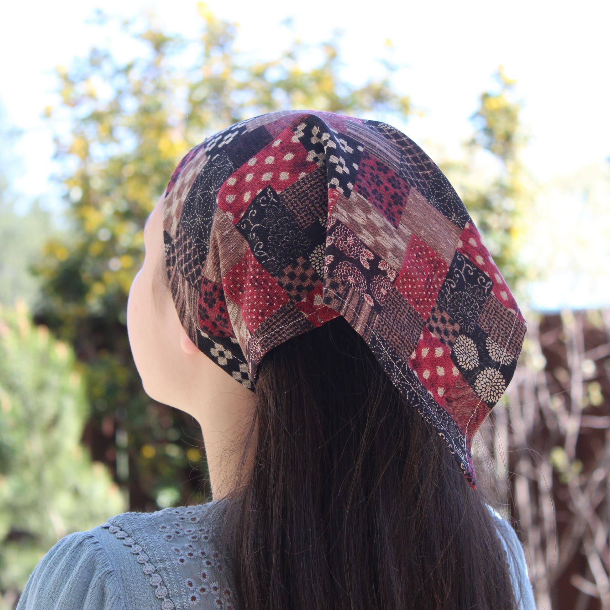 Person wearing a colorful patterned headscarf with a blurred natural background