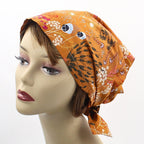 Mannequin head wearing an orange patterned headscarf on a white background