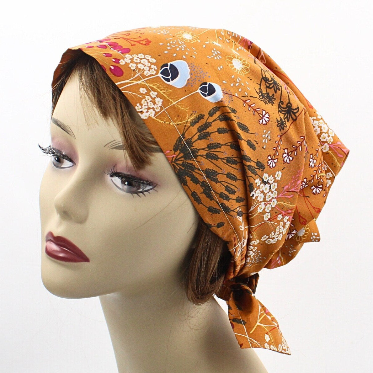 Mannequin head wearing an orange patterned headscarf on a white background